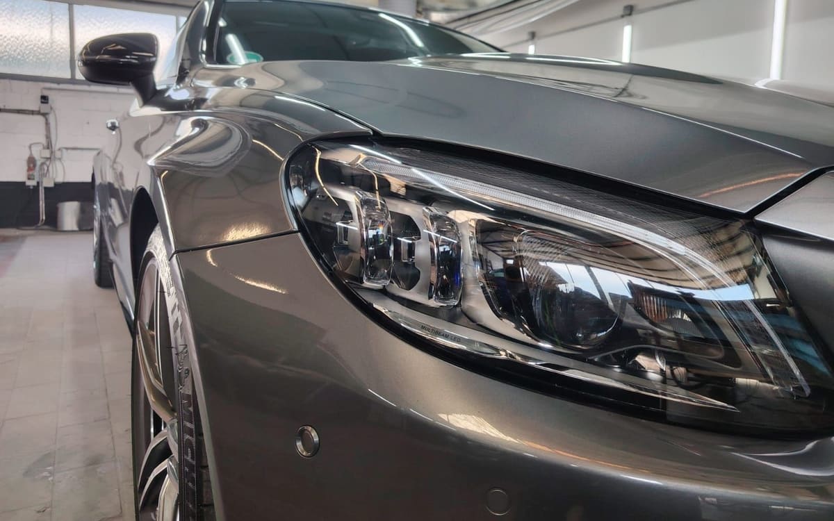 Front eines grauen Mercedes AMG Coupés mit glänzendem Lack in der Werkstatt